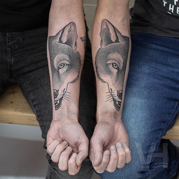Two forearm symmetrical tattoos of a wolf's face by Valentin Hirsch, blending nature and geometry.