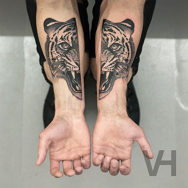Symmetrical tattoos by Valentin Hirsch depicting a tiger, blending nature and geometry on forearms.