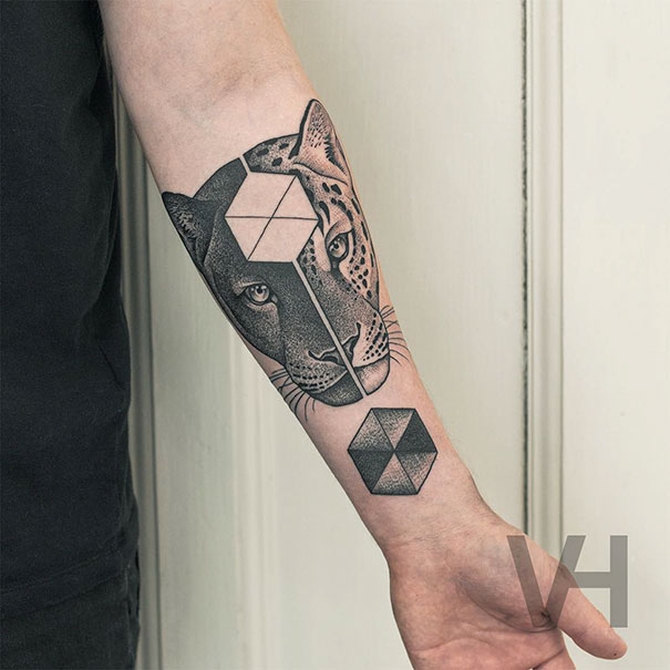 Symmetrical tattoo by Valentin Hirsch on forearm blends nature with geometric shapes, featuring a leopard face and hexagons.