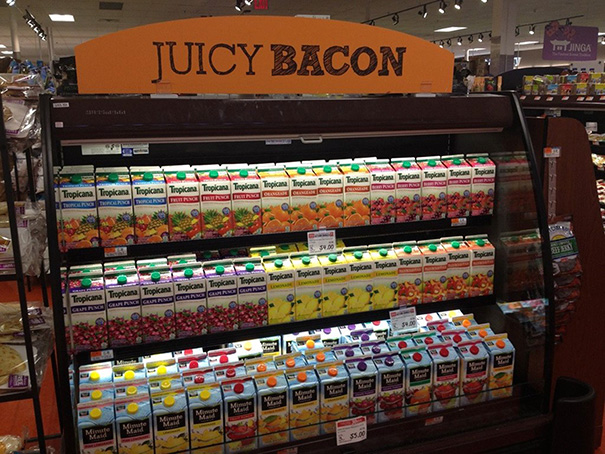 Display fail with juice cartons under a "Juicy Bacon" sign in a store shelf.