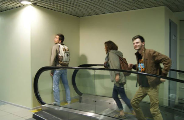 Three people walking up a non-functioning escalator, illustrating a funny fail moment.