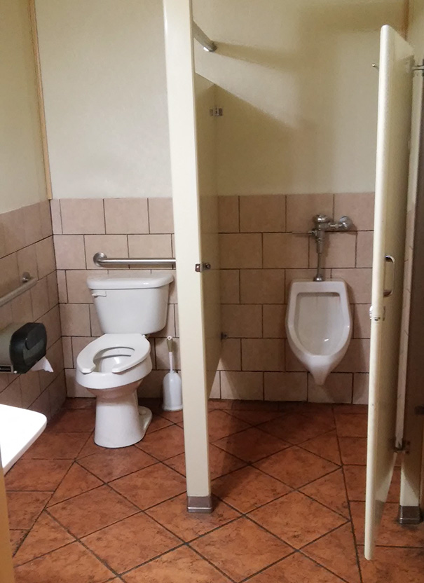Bathroom fail with toilet and urinal awkwardly placed together, illustrating a job not done right.