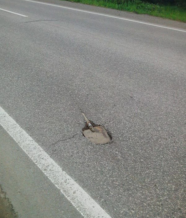 Road repair fail with a shovel stuck upright in the pavement.