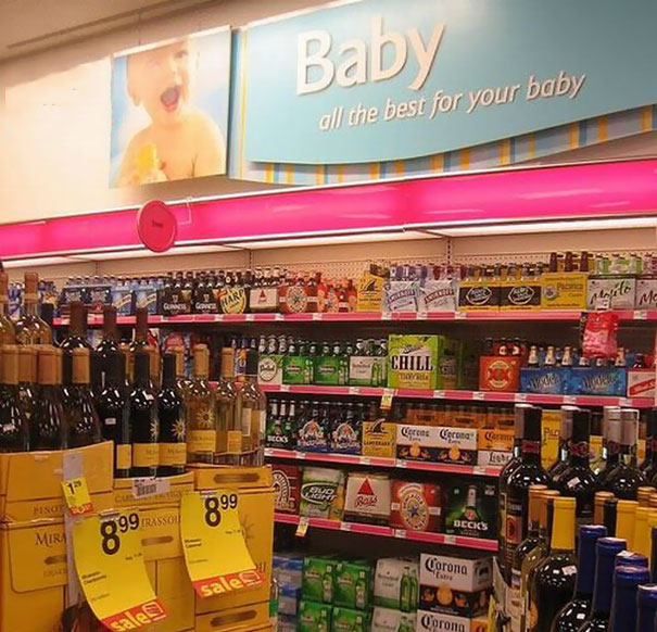 Store display fail with baby section sign over alcohol shelves.