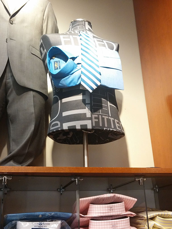 Mannequin with a tie and shirt on its chest, incorrectly assembled, in a clothing store display; failed job e*******n.