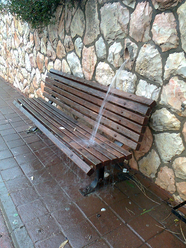 Water fountain misaligned, spraying directly onto a wooden bench, showcasing a clear job fail.