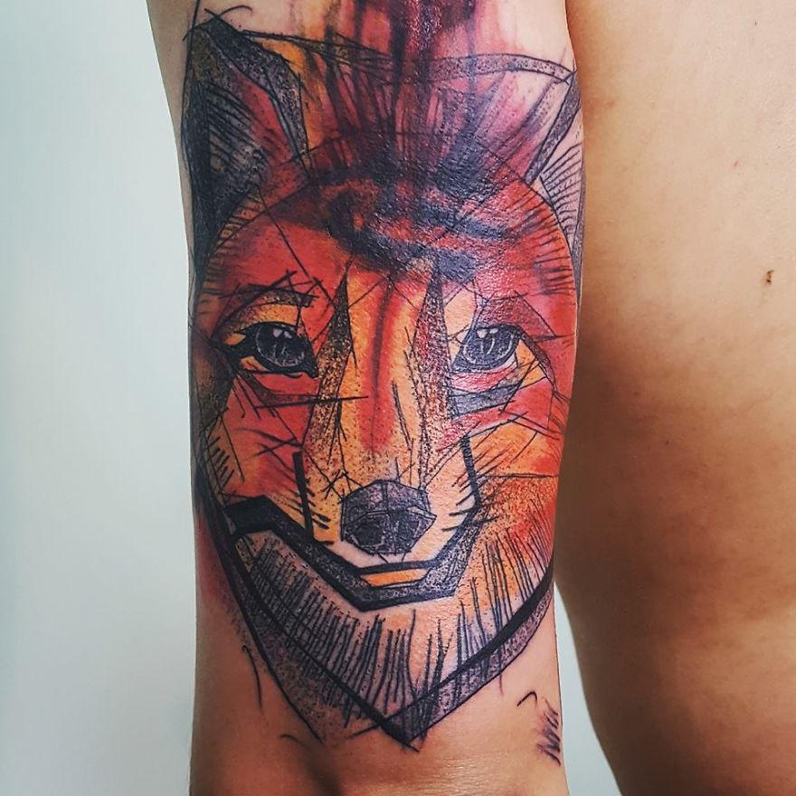 Colorful sketchy tattoo of a fox illustrated with geometric patterns on a person's forearm.