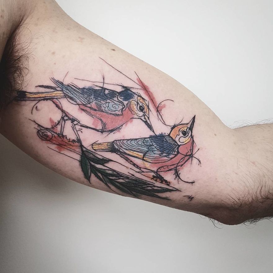Colorful sketchy bird tattoos on an arm, showcasing artistic detail and vibrant design.