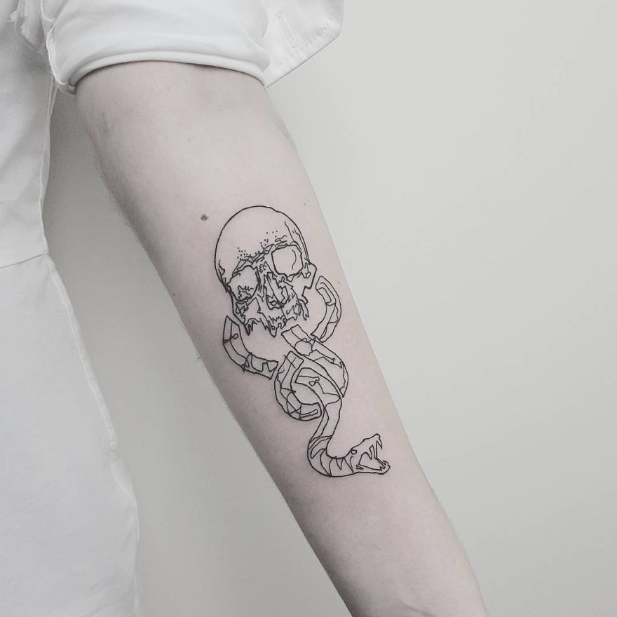 Arm displaying a sketchy tattoo of a skull entwined with a snake.