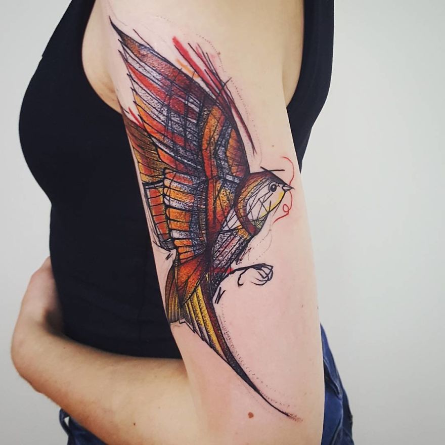 Colorful sketchy tattoo of a bird on a person's arm, featuring dynamic lines and vibrant hues.