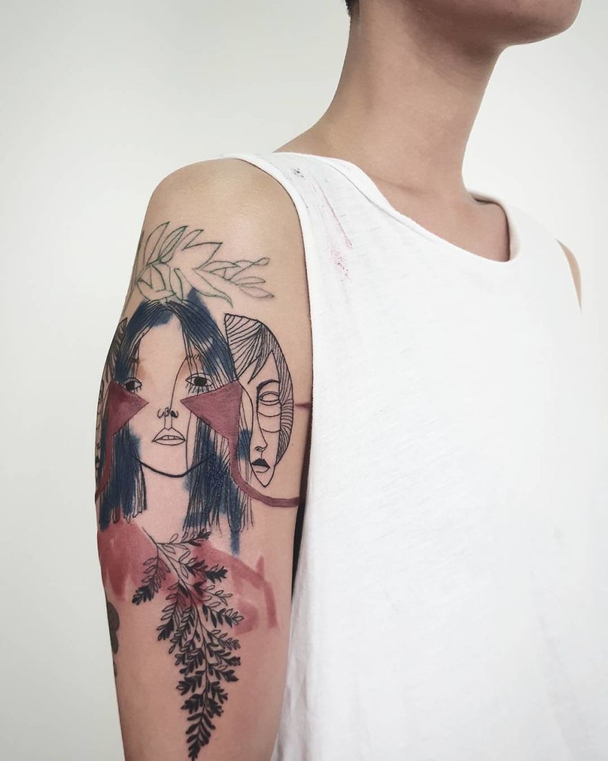 Colorful sketchy tattoo of abstract faces and leaves on a person's upper arm.