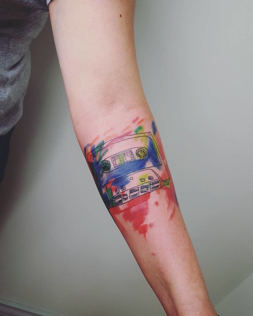 Arm with a colorful, sketchy tattoo of a cassette tape.