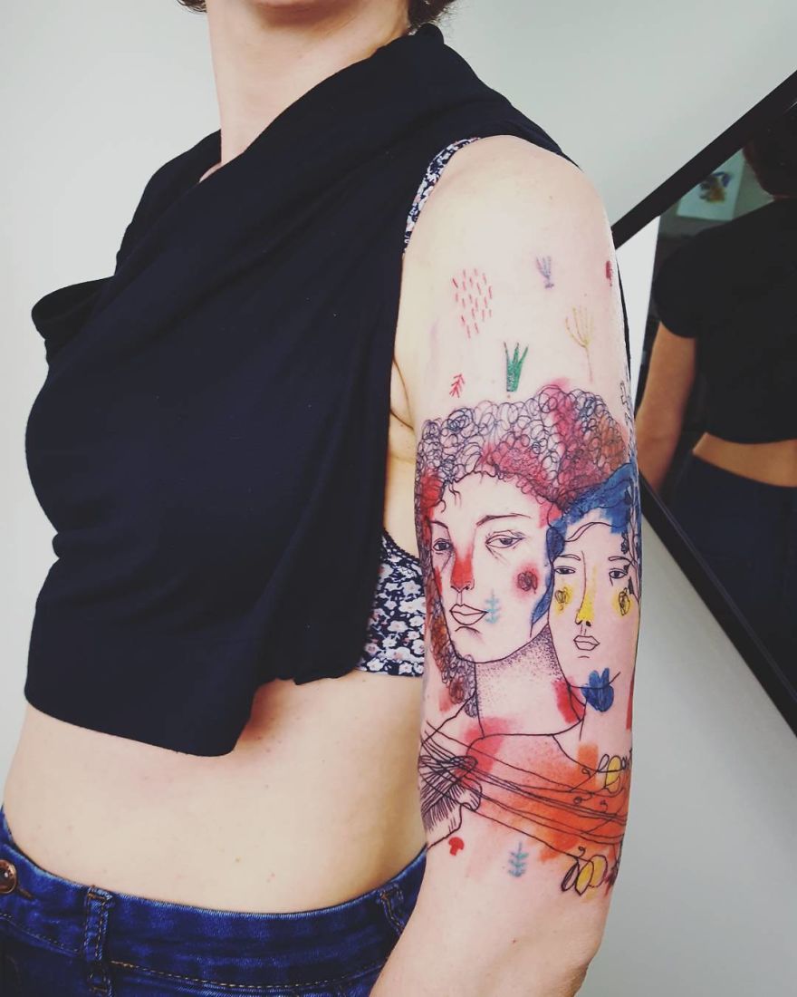 Colorful and sketchy tattoo featuring abstract faces on a person's upper arm.