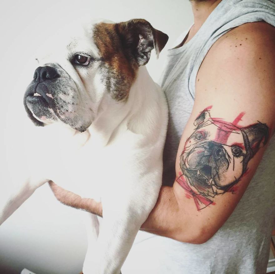 A person holding a bulldog with a colorful and sketchy tattoo of the dog on their arm.