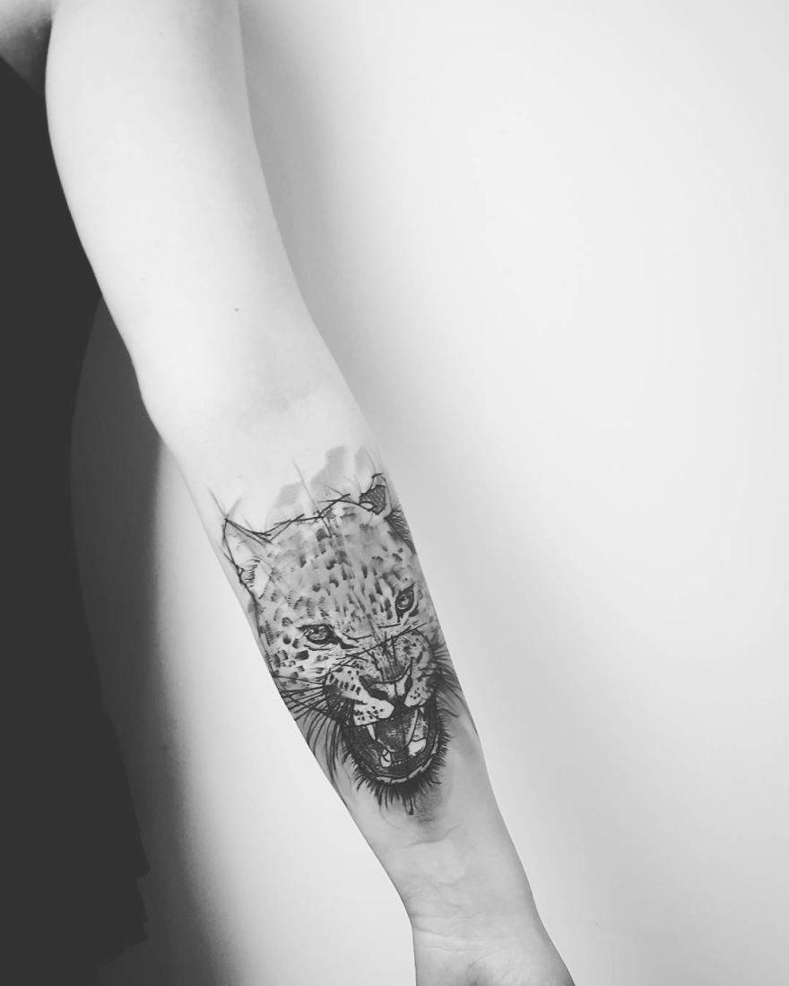 Sketchy tattoo of a roaring leopard on a person's inner forearm, featuring detailed line work and shading.