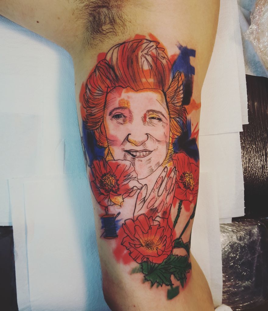 Colorful sketchy tattoo by Vesna featuring a smiling face and vibrant red flowers on an arm.