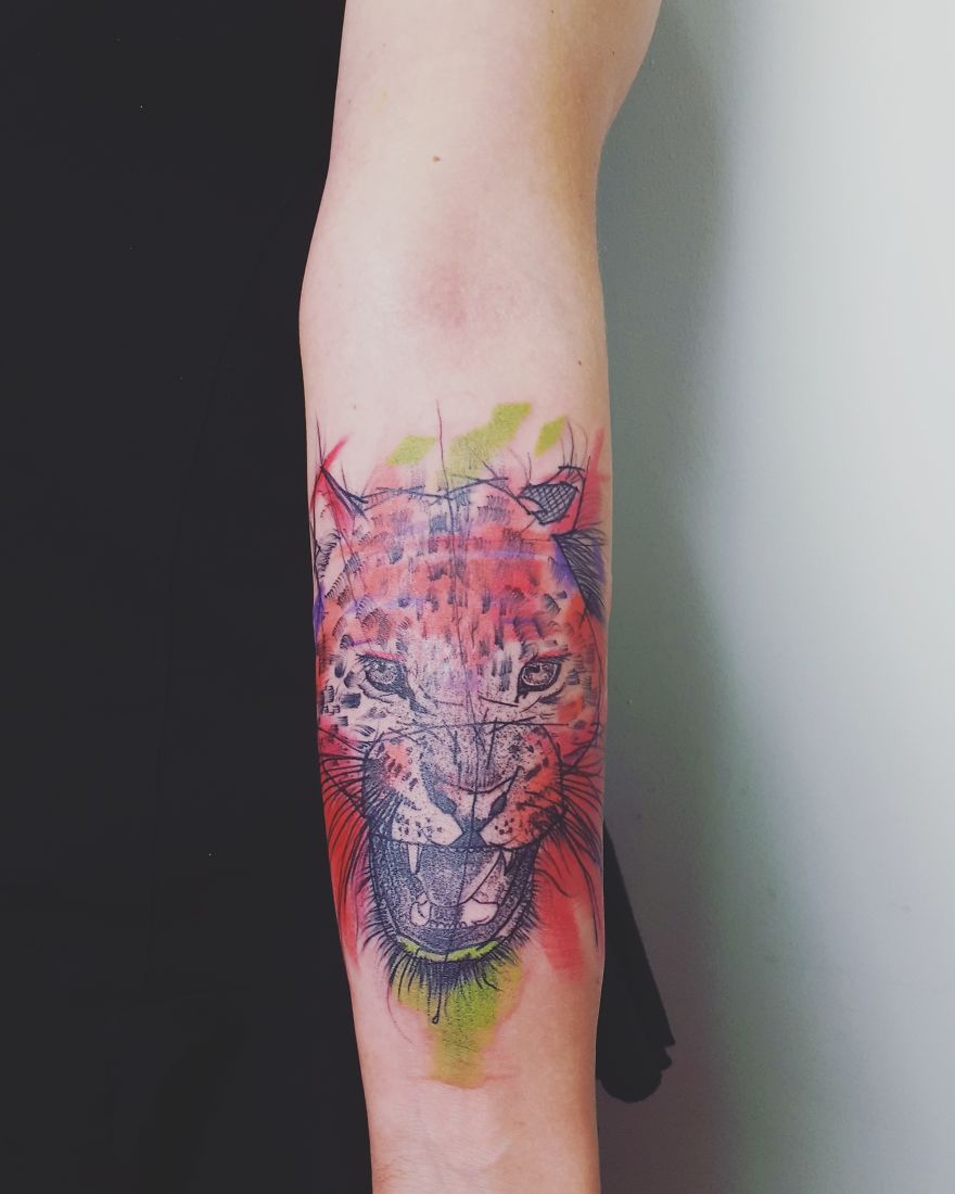 Tattoo of a colorful, sketchy leopard design on a forearm, showcasing vibrant hues and artistic style.