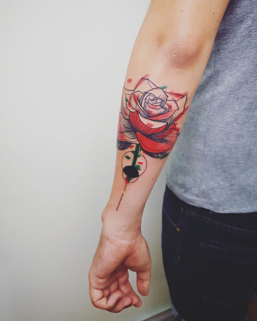 Colorful and sketchy rose tattoo on a person's arm with geometric elements.