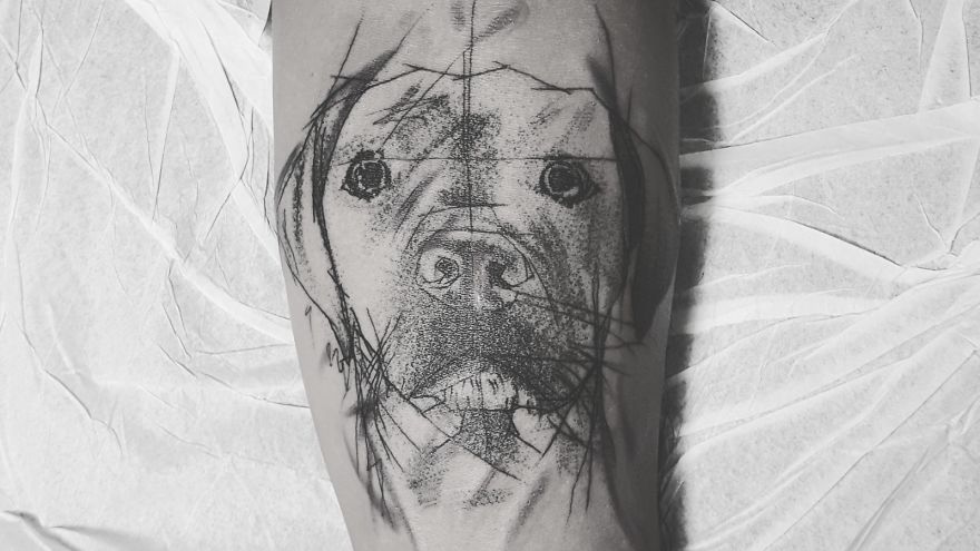 Sketchy tattoo of a dog's face on an arm, featuring artistic lines and shading.