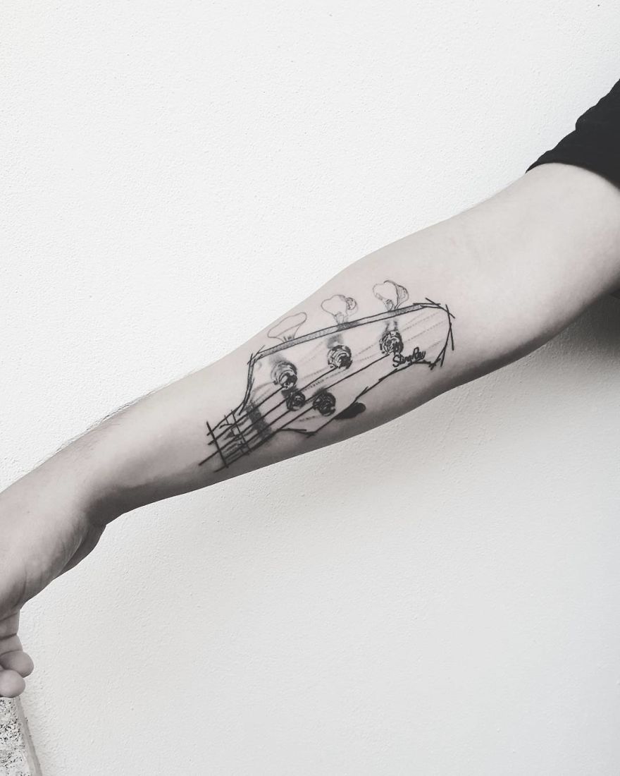 Sketchy tattoo of a guitar head on forearm, illustrating Vesna's artistic style.