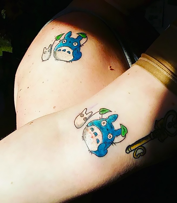 Trio tattoos featuring Totoro characters on arms, colorful and playful design with key detail.