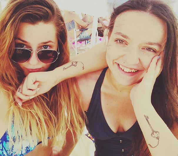 Two friends showing matching key tattoos on their arms, symbolizing trio tattoos and friendship.