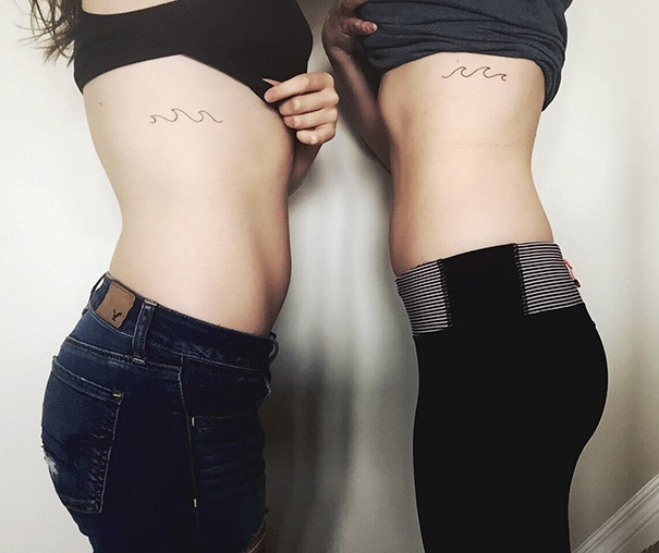Two people showing matching wave trio tattoos on their side ribs.