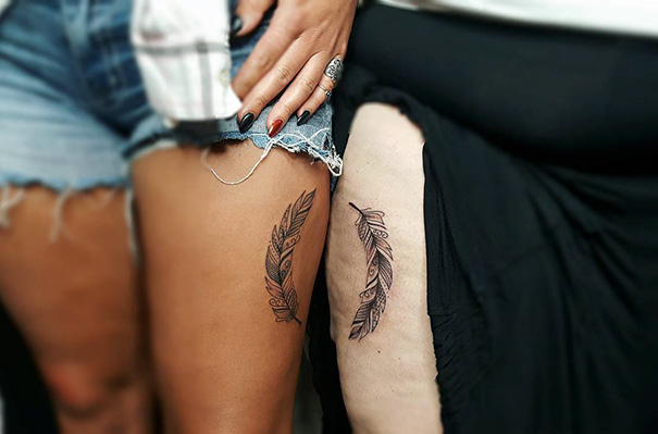 Feather trio tattoos on thighs, showcasing detailed, matching designs with a bohemian style.