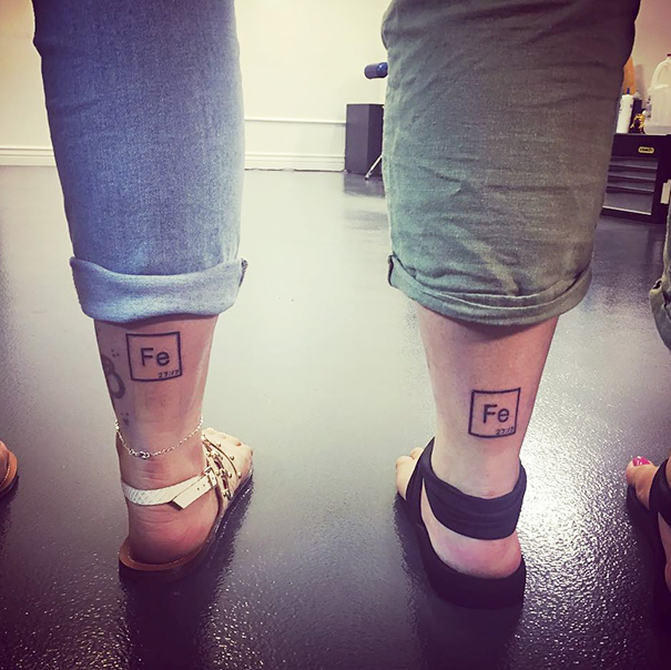 Two people with matching 'Fe' element tattoos on their legs, showcasing trio tattoo ideas.