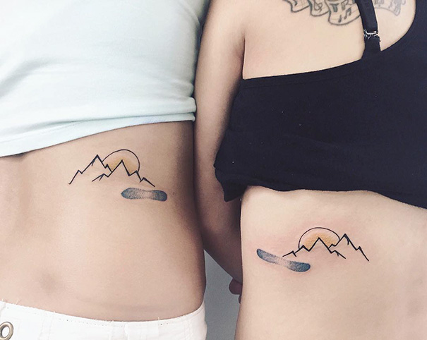 Two people with matching trio tattoos of mountains and a sun on their ribs, showcasing creative tattoo designs.