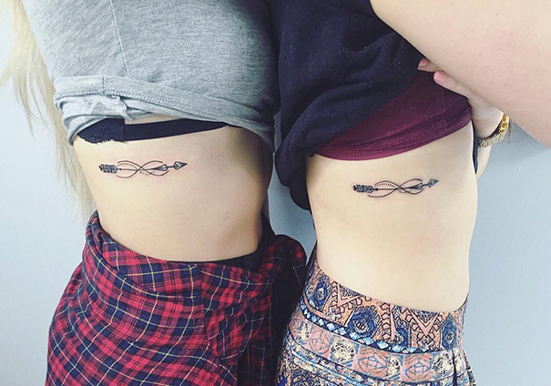 Two individuals with matching trio tattoos featuring arrows entwined on their sides, showcasing friendship-themed body art.