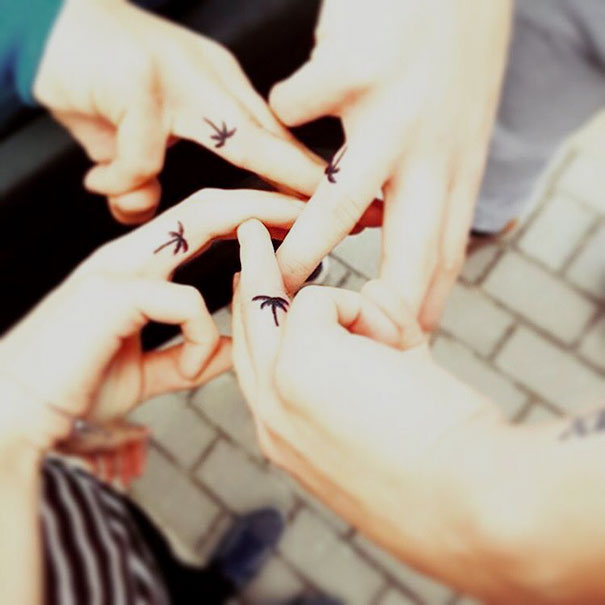 Three hands with matching small trio tattoos on fingers, symbolizing unity and friendship.