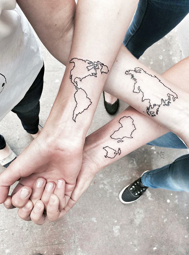 Three forearms with trio tattoos of world map outlines in a triangle formation, symbolizing unity and connectedness.
