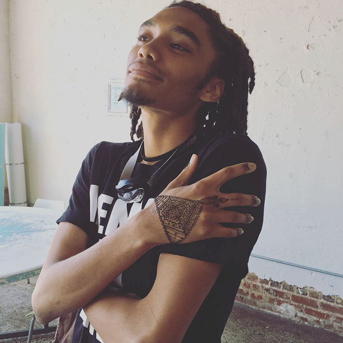 Man showcasing intricate henna tattoos on his hand, embodying the 'Menna' trend in a casual setting.