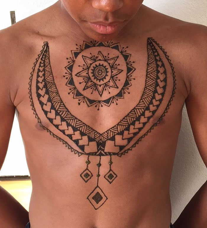 Man with intricate henna tattoos on chest showcasing 'Menna' trend.