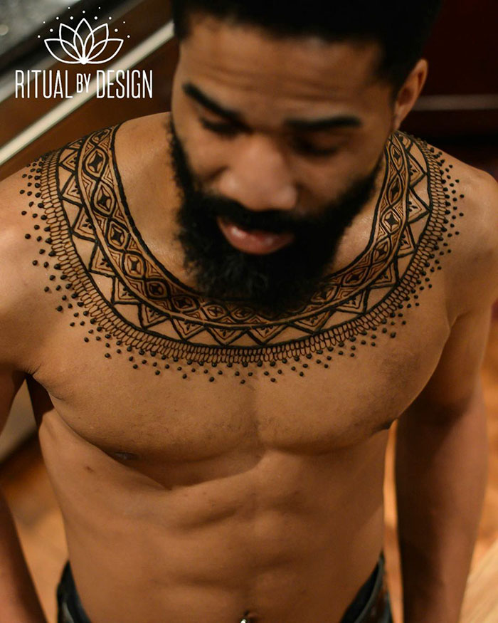 Man showcasing intricate henna tattoos on chest, highlighting the Menna trend for men's body art.
