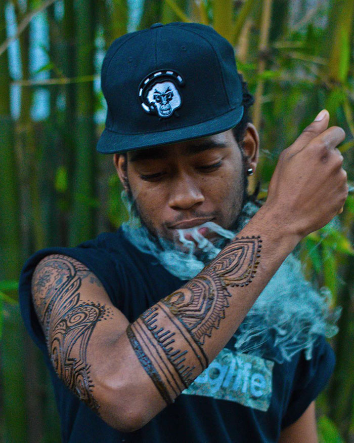 Man wearing intricate henna tattoos on his arm, showcasing the Menna trend.