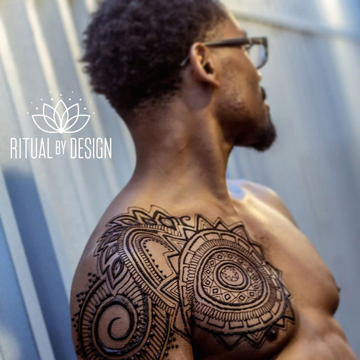Man with intricate henna design on shoulder, embracing 'Menna' trend, photographed by Ritual by Design.