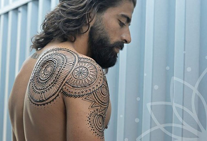 Man with intricate henna tattoo on shoulder, showcasing the 'Menna' trend.