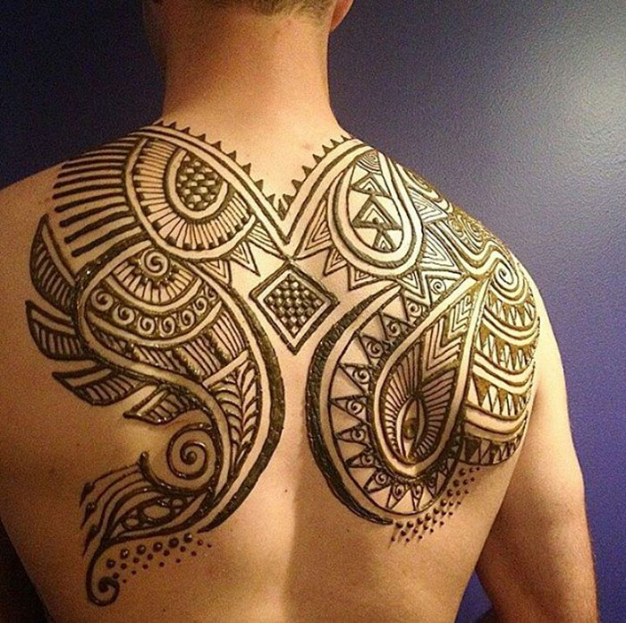 Man showcasing intricate "Menna" henna tattoo design on his back.