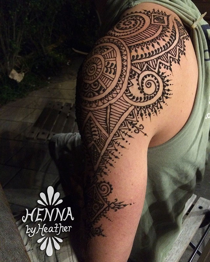 Man showcasing intricate henna tattoo on his arm, part of the 'Menna' trend.