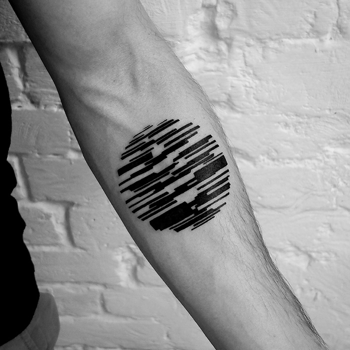 Minimalist digitally-designed tattoo on a forearm, featuring abstract black lines in a circular pattern.