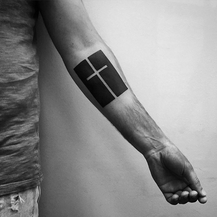 Minimalist digitally-designed tattoo featuring a cross on a person's forearm.