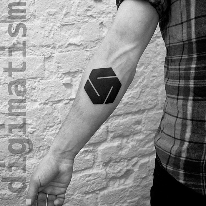 Minimalist digitally-designed tattoo on a person's forearm in black ink against a brick wall background.