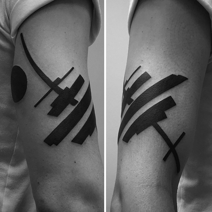 Minimalist digitally-designed tattoos on an arm, featuring abstract geometric shapes in bold black ink.