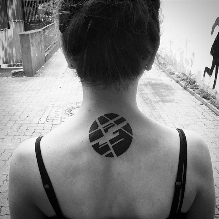 Minimalist digitally-designed tattoo on a woman's upper back in a geometric circular pattern.