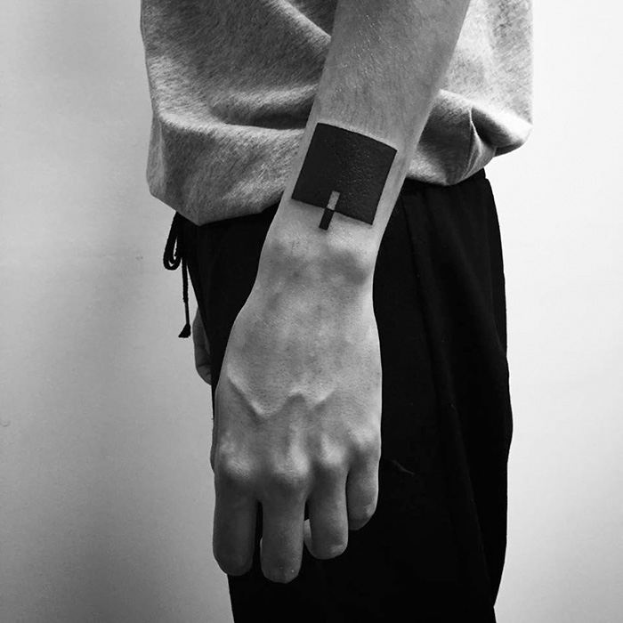 Minimalist digitally-designed tattoo of a black square on a forearm, created by Russian artist.