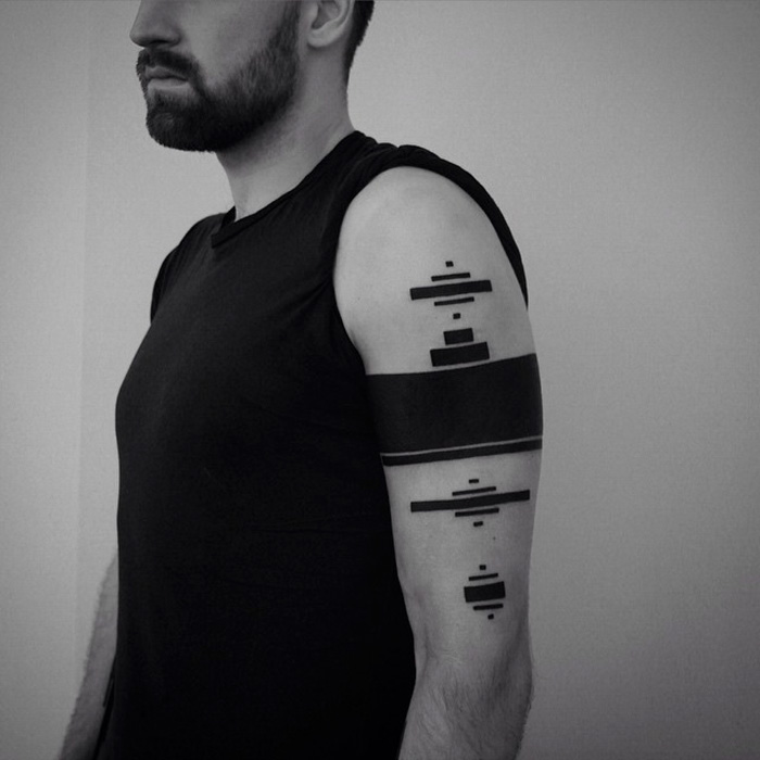 A minimalist digitally-designed tattoo featuring geometric shapes on a man's arm.