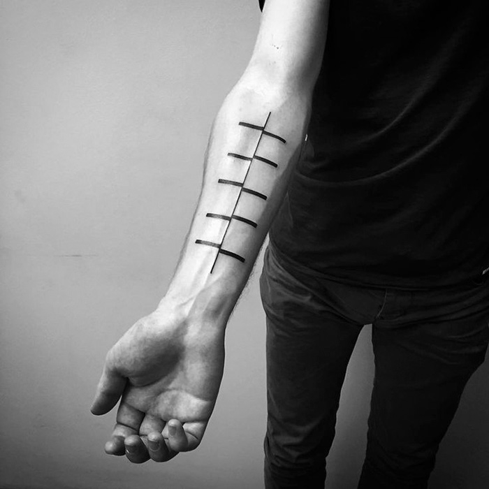 Minimalist tattoo design featuring lines on a person's forearm, created by a Russian artist.