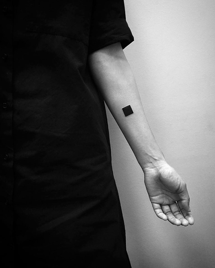 Minimalist digitally-designed tattoo of a black square on a person's forearm by Russian artist.